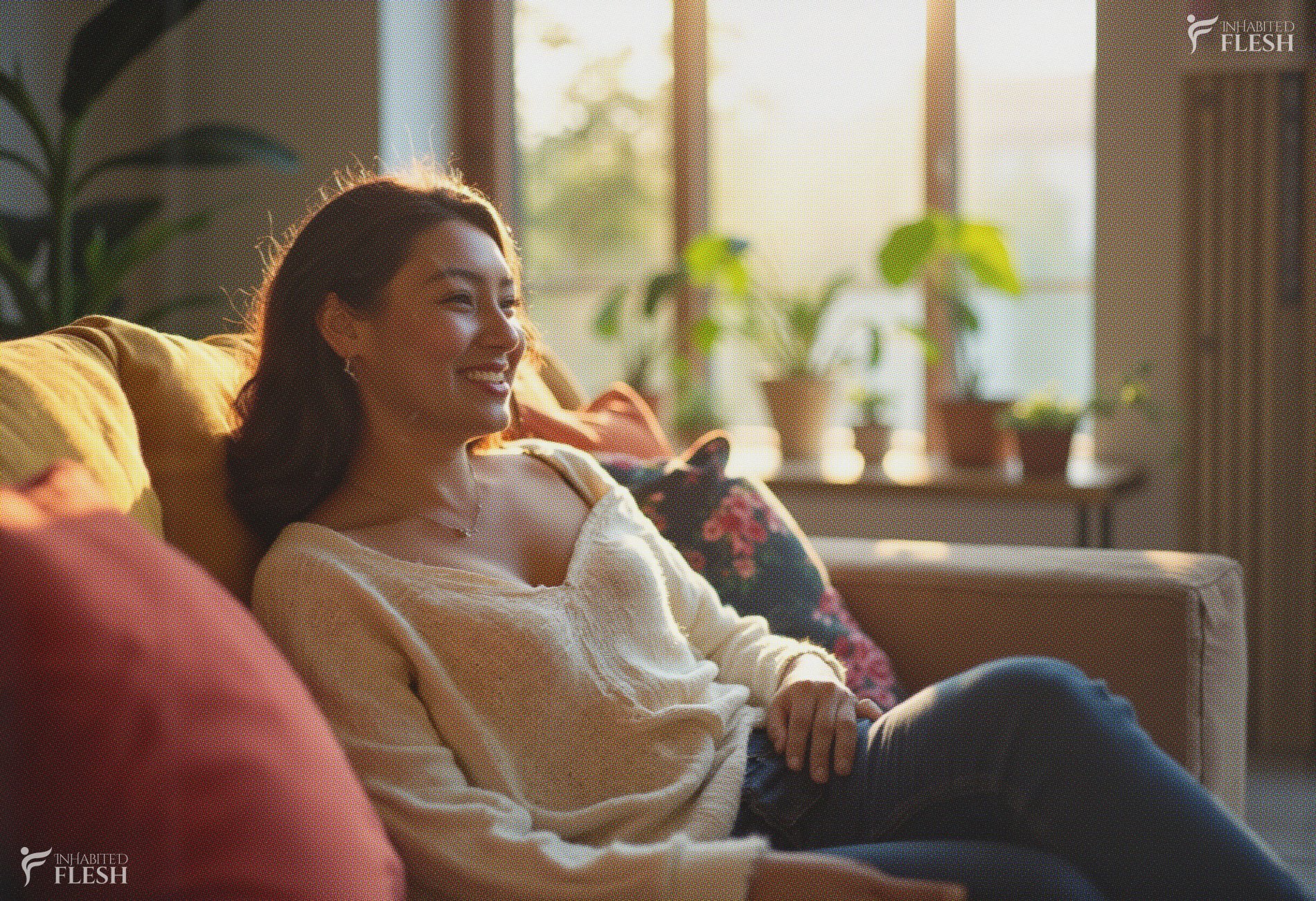A woman lounging comfortably on a cozy living room sofa, radiating joy and relaxation as she leans back with a warm smile, wearing a light beige sweater and dark jeans, surrounded by soft sunlight streaming through large windows adorned with potted plants.